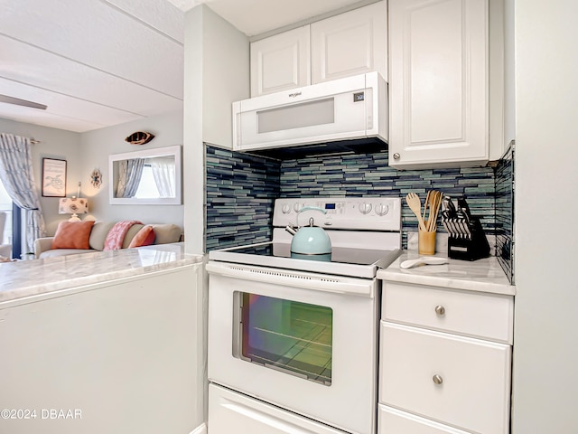 kitchen with backsplash, white appliances, and white cabinets