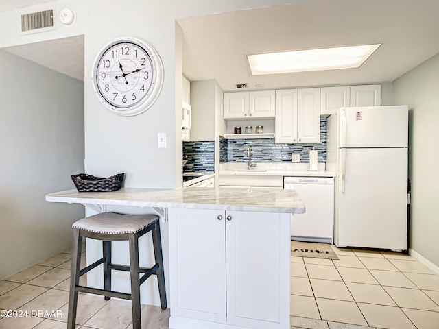 kitchen featuring tasteful backsplash, white cabinetry, light tile patterned floors, sink, and white appliances