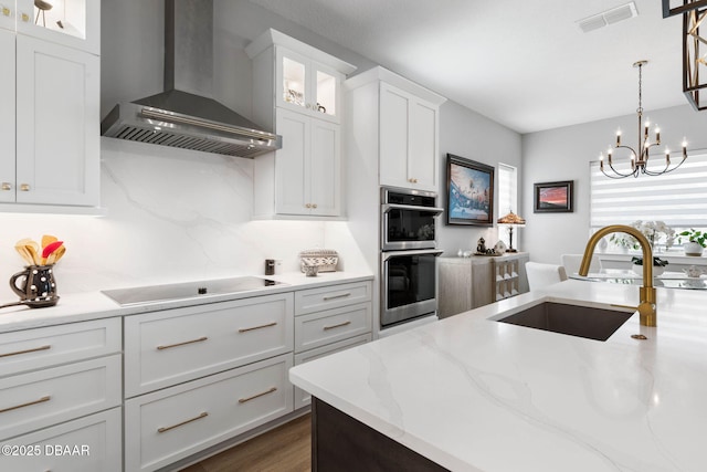 129 Seaside Pt, Flagler Beach, FL 32136 - kitchen featuring wall chimney range hood, black electric cooktop, stainless steel double oven, white cabinets, and glass insert cabinets