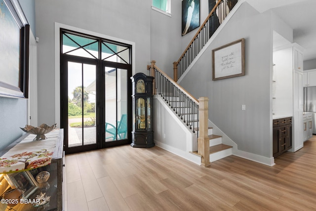 129 Seaside Pt, Flagler Beach, FL 32136 - entrance foyer with light wood-style flooring, a towering ceiling, and stairs