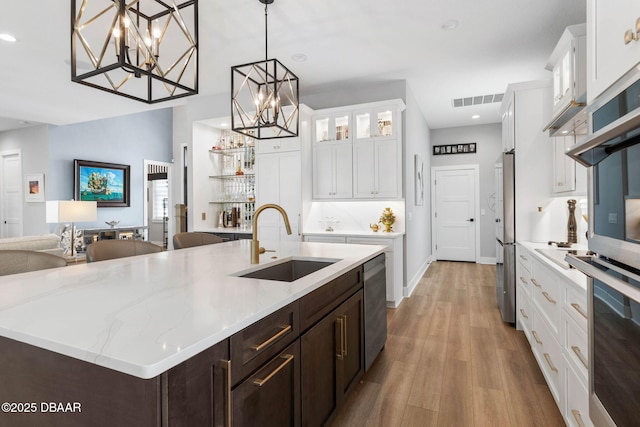 129 Seaside Pt, Flagler Beach, FL 32136 - kitchen featuring dark brown cabinetry, light wood finished floors, white cabinetry, a center island with sink, and recessed lighting