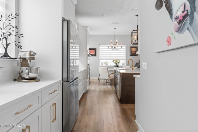 129 Seaside Pt, Flagler Beach, FL 32136 - kitchen with freestanding refrigerator, dark wood finished floors, white cabinetry, a chandelier, and pendant lighting