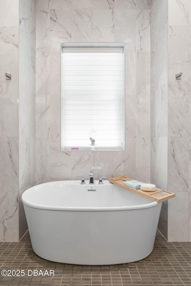129 Seaside Pt, Flagler Beach, FL 32136 - bathroom featuring tile walls, a freestanding tub, and tile patterned flooring