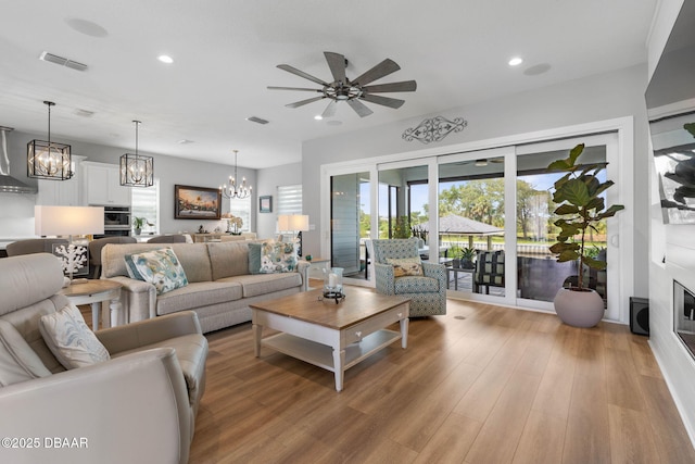 129 Seaside Pt, Flagler Beach, FL 32136 - living room with a chandelier, recessed lighting, light wood-style flooring, a ceiling fan, and a glass covered fireplace