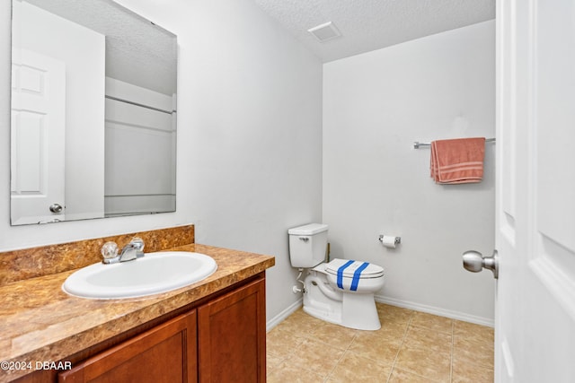 bathroom with tile patterned flooring, vanity, a textured ceiling, and toilet