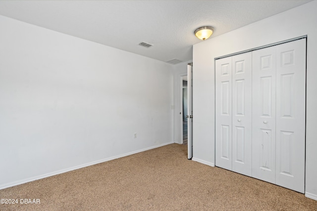 unfurnished bedroom with carpet, a textured ceiling, and a closet