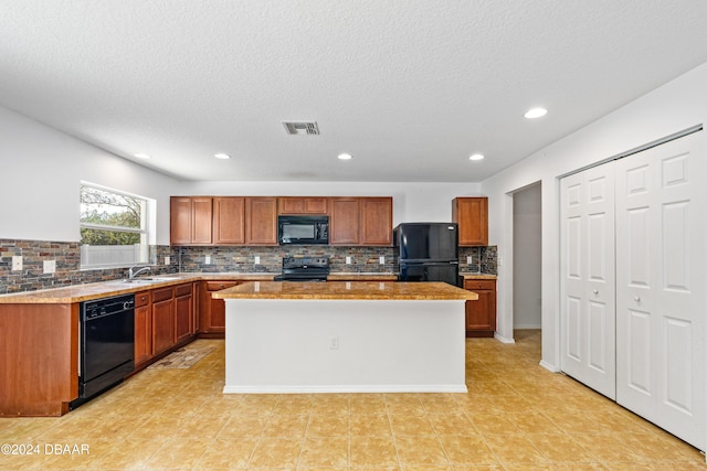 kitchen with black appliances, a center island, and a textured ceiling