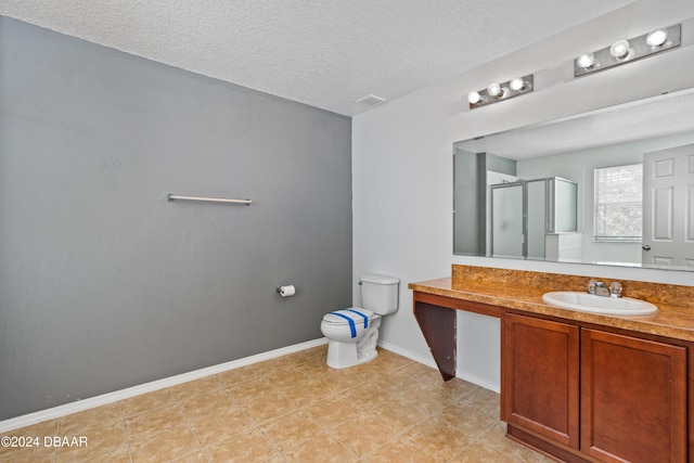 bathroom with vanity, a textured ceiling, toilet, and a shower with shower door