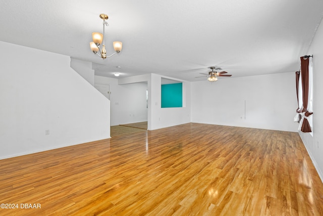 unfurnished living room with ceiling fan with notable chandelier and light hardwood / wood-style floors