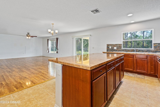 kitchen featuring a center island, a healthy amount of sunlight, backsplash, hanging light fixtures, and light tile patterned flooring