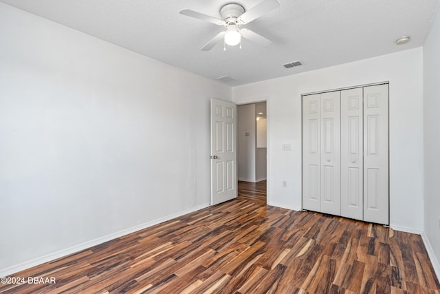 unfurnished bedroom with ceiling fan, dark hardwood / wood-style floors, a textured ceiling, and a closet