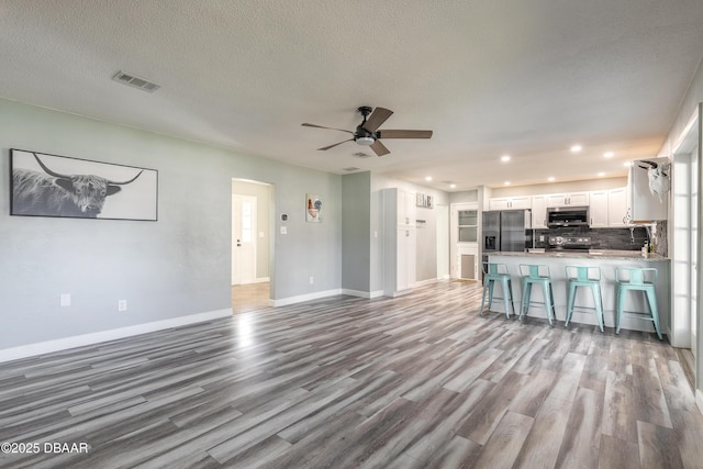 unfurnished living room featuring ceiling fan, a textured ceiling, and light wood-type flooring