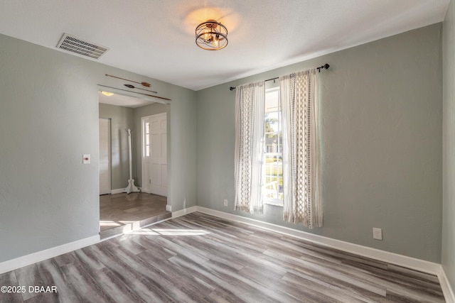 unfurnished room featuring light hardwood / wood-style floors and a textured ceiling