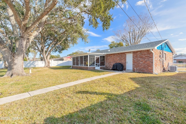 back of house with central AC, a lawn, and a sunroom