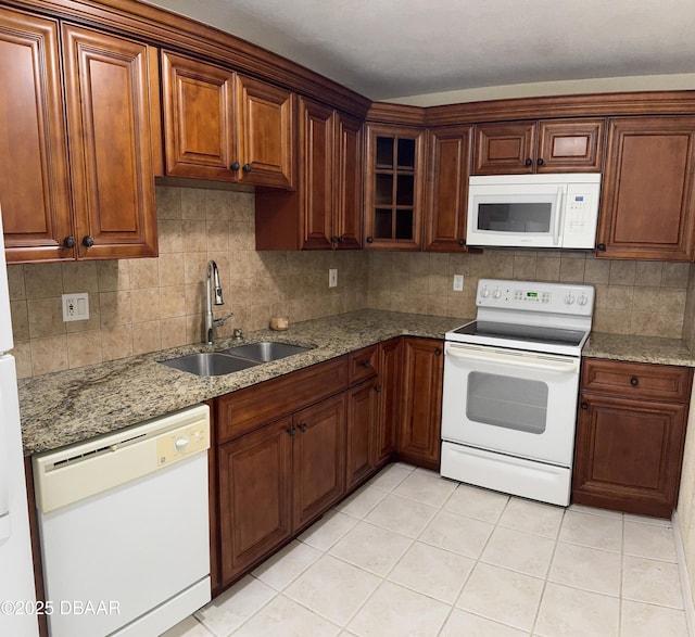 kitchen with sink, white appliances, light tile patterned floors, tasteful backsplash, and light stone countertops