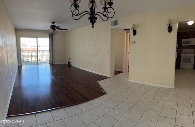 unfurnished room with ceiling fan with notable chandelier and light tile patterned floors