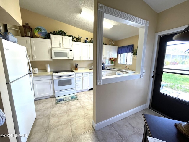 kitchen featuring white appliances, lofted ceiling, a healthy amount of sunlight, and white cabinets