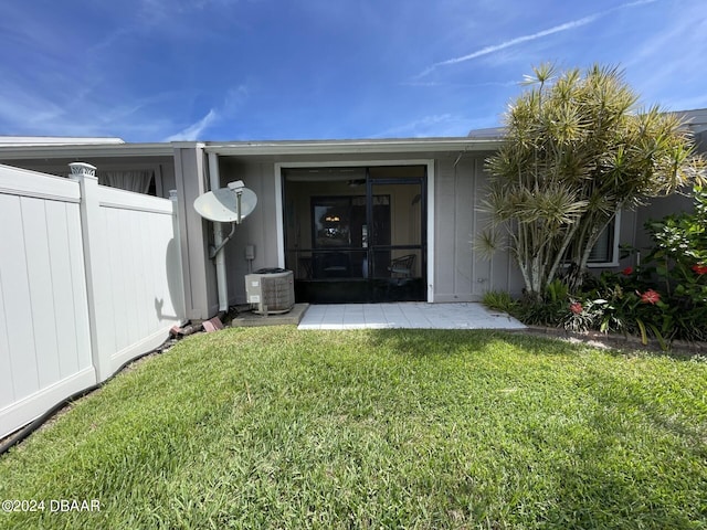 entrance to property with central AC unit and a yard