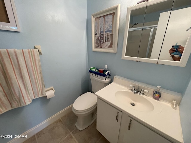 bathroom featuring tile patterned flooring, vanity, toilet, and a shower with shower door