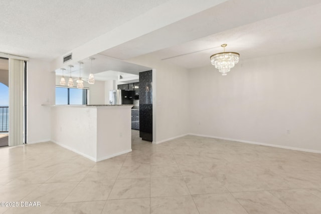 3003 S Atlantic Ave Unit 16B3, Daytona Beach Shores, FL 32118 - kitchen featuring a chandelier, stainless steel fridge, a peninsula, pendant lighting, and baseboards