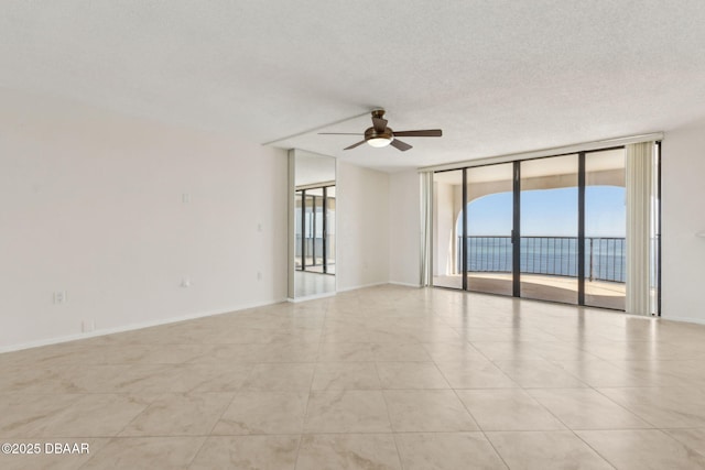 3003 S Atlantic Ave Unit 16B3, Daytona Beach Shores, FL 32118 - unfurnished room with expansive windows, ceiling fan, light tile patterned flooring, baseboards, and a textured ceiling