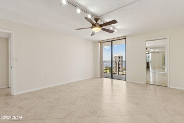 3003 S Atlantic Ave Unit 16B3, Daytona Beach Shores, FL 32118 - empty room featuring a ceiling fan, expansive windows, a textured ceiling, light tile patterned floors, and baseboards