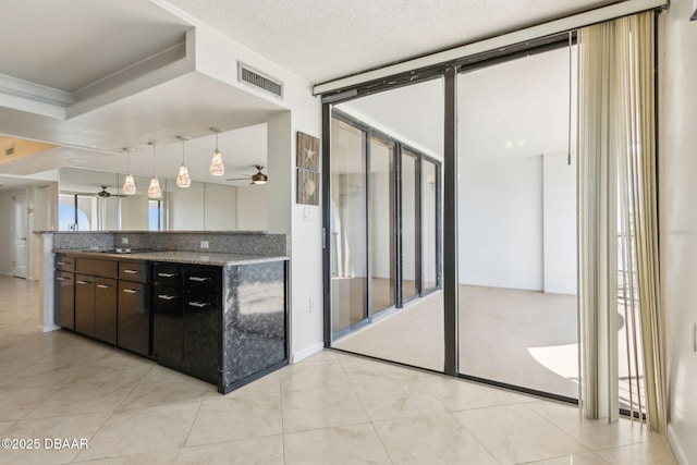 3003 S Atlantic Ave Unit 16B3, Daytona Beach Shores, FL 32118 - kitchen featuring a ceiling fan, light tile patterned floors, hanging light fixtures, light stone counters, and dark brown cabinetry