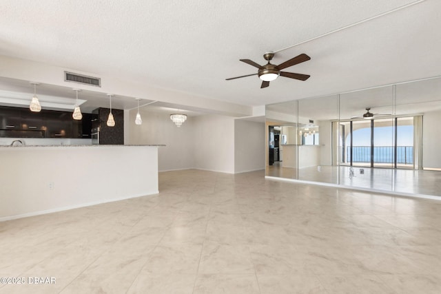 3003 S Atlantic Ave Unit 16B3, Daytona Beach Shores, FL 32118 - unfurnished living room with ceiling fan, a textured ceiling, a wall of windows, and a chandelier