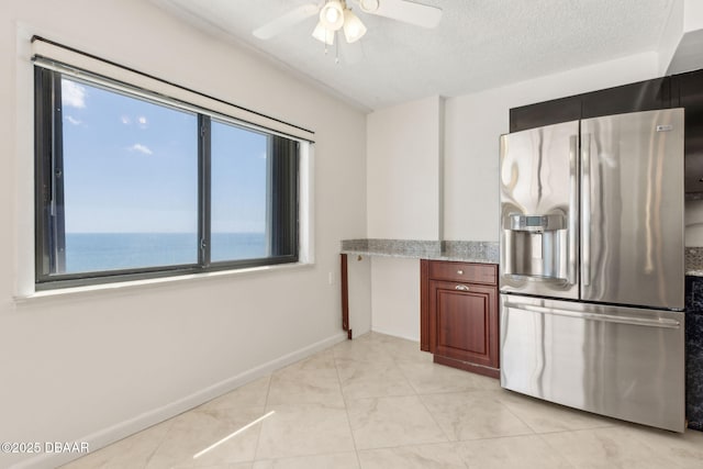 3003 S Atlantic Ave Unit 16B3, Daytona Beach Shores, FL 32118 - kitchen featuring stainless steel refrigerator with ice dispenser, a ceiling fan, baseboards, light stone counters, and a textured ceiling