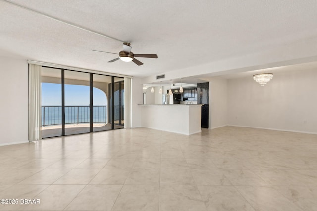 3003 S Atlantic Ave Unit 16B3, Daytona Beach Shores, FL 32118 - unfurnished living room with expansive windows, a ceiling fan, a chandelier, baseboards, and a textured ceiling