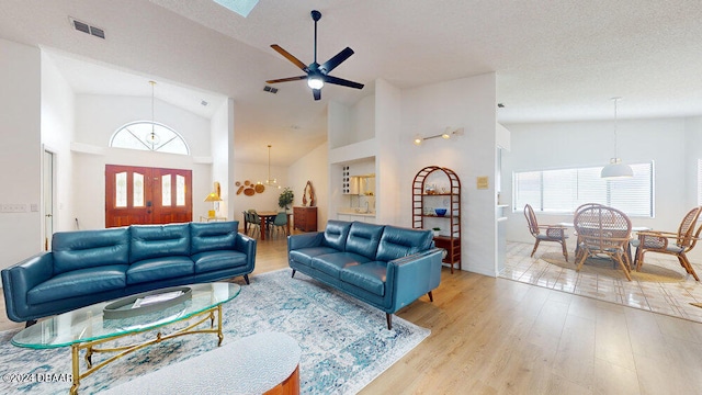 living room with light hardwood / wood-style floors, a textured ceiling, and high vaulted ceiling