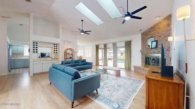 living room featuring high vaulted ceiling, light wood-type flooring, ceiling fan, and a fireplace