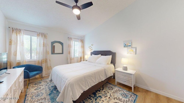 bedroom featuring light hardwood / wood-style flooring, multiple windows, ceiling fan, and vaulted ceiling