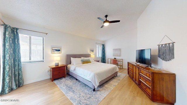 bedroom featuring light wood-type flooring, vaulted ceiling, ceiling fan, and a textured ceiling