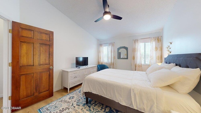 bedroom featuring light hardwood / wood-style floors, vaulted ceiling, ceiling fan, and a textured ceiling