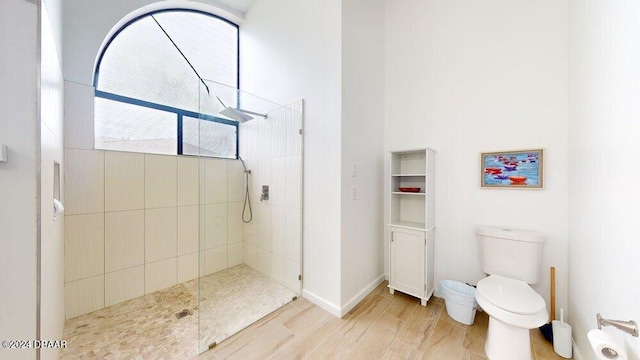 bathroom with hardwood / wood-style floors, toilet, and tiled shower