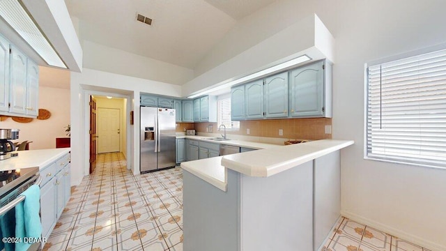 kitchen featuring kitchen peninsula, appliances with stainless steel finishes, lofted ceiling, and plenty of natural light