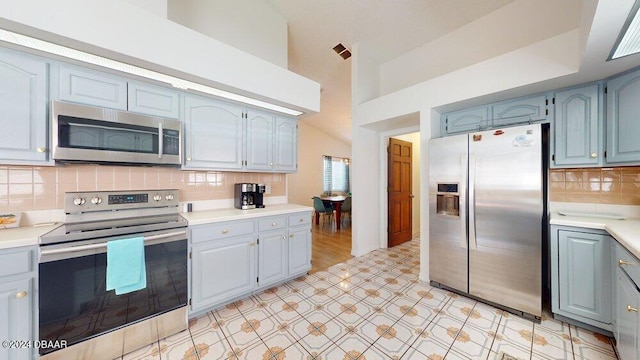 kitchen featuring high vaulted ceiling, appliances with stainless steel finishes, and decorative backsplash