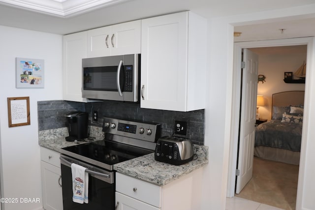 kitchen with stainless steel appliances, white cabinets, light stone counters, and tasteful backsplash