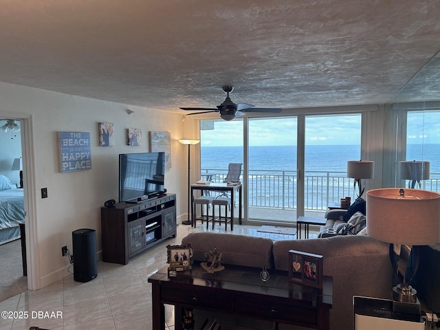 living area with a ceiling fan, baseboards, and light tile patterned floors