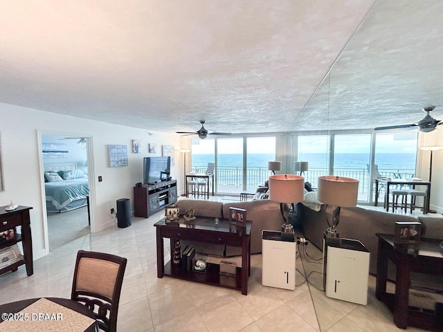 living area featuring light tile patterned floors, a wealth of natural light, and a ceiling fan