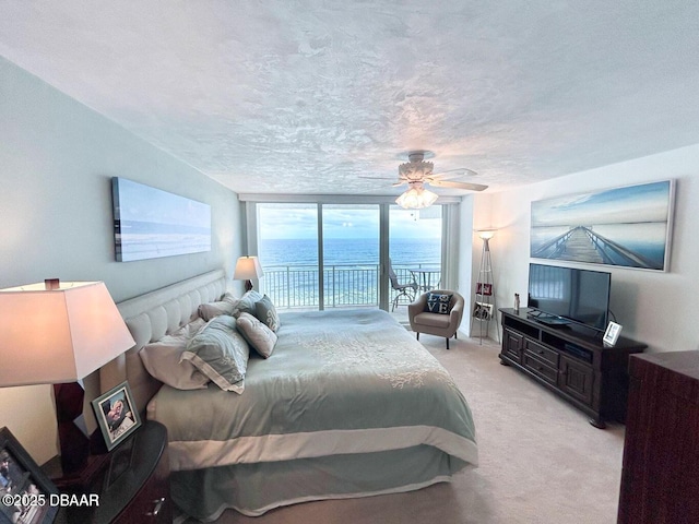 bedroom with light carpet, access to exterior, a wall of windows, and a textured ceiling