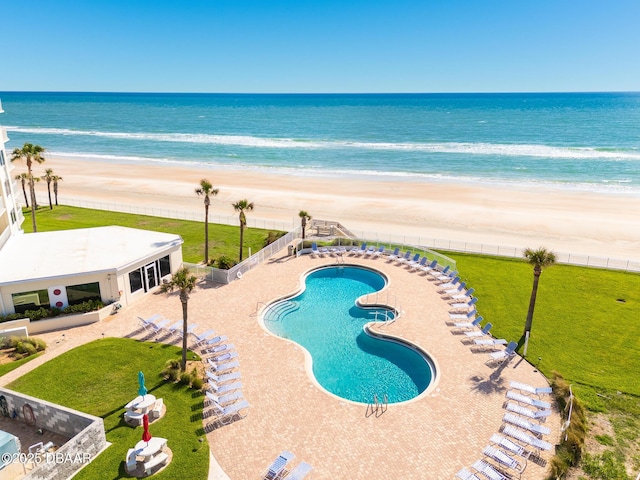 view of pool with a patio area, a water view, and a beach view