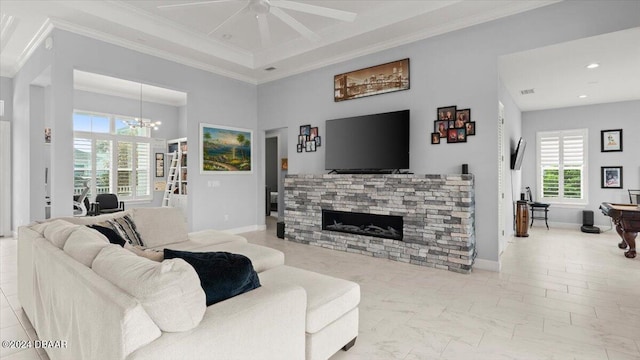 living room featuring a stone fireplace, ceiling fan with notable chandelier, and ornamental molding