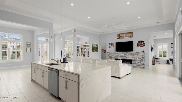 kitchen with white cabinets, sink, a kitchen island with sink, stainless steel dishwasher, and a fireplace