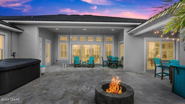 patio terrace at dusk featuring an outdoor fire pit and a hot tub