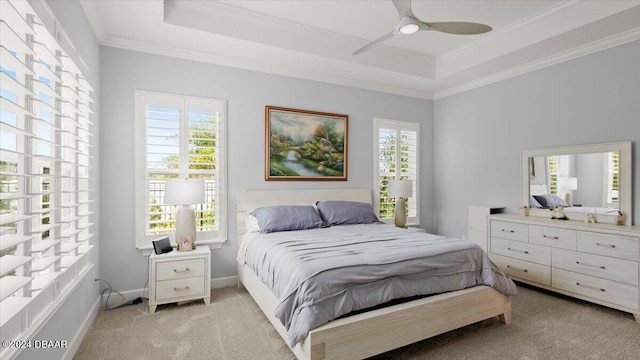 bedroom featuring ornamental molding, light carpet, ceiling fan, and a tray ceiling