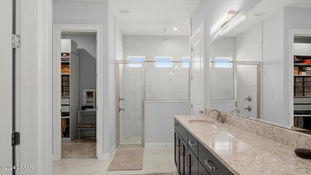 bathroom featuring a shower with shower door and vanity