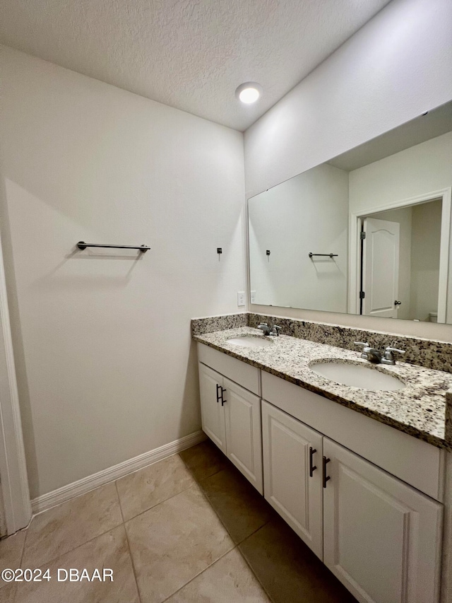 bathroom with tile patterned flooring, vanity, and a textured ceiling