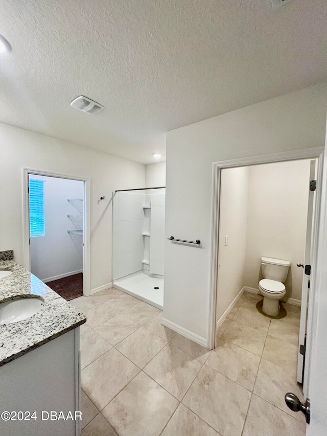 bathroom featuring vanity, a textured ceiling, toilet, and a shower